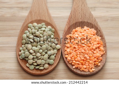 Green and red lentils in a wooden spoons. Close-up.