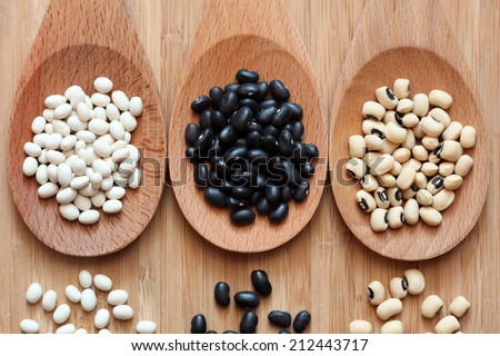 Beans in a wooden spoons: white beans, black beans and black eyed peas.