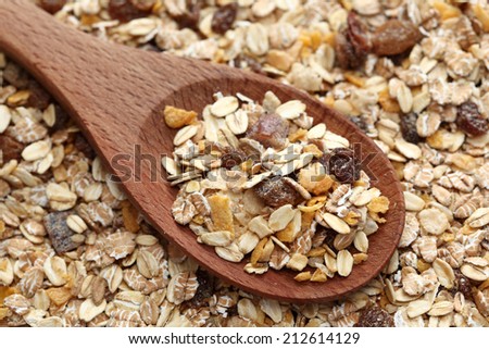Muesli in a wooden spoon on muesli background. Close-up.
