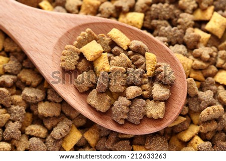 Cat food in a wooden spoon on cat food background. Close-up.