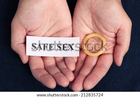 Woman\'s hands hold a condom and a piece of paper with the words \