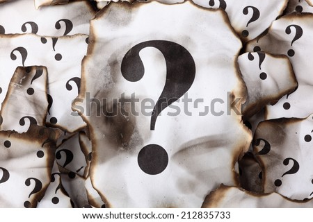Burnt Question Marks. Burnt pieces of paper with the question mark. Close-up.