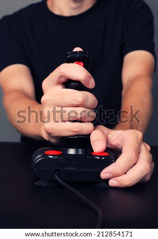 Young man plays video game with a retro joystick. Gaming joystick from the mid-1980s. Joystick with dust particles and scratches.