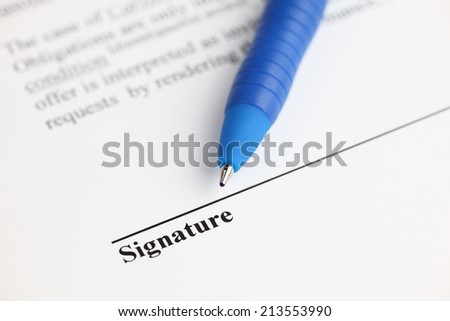 Contract ready for signature. Ballpoint pen on contract. Focus on the end of ballpoint pen. Shallow depth of field. Closeup.