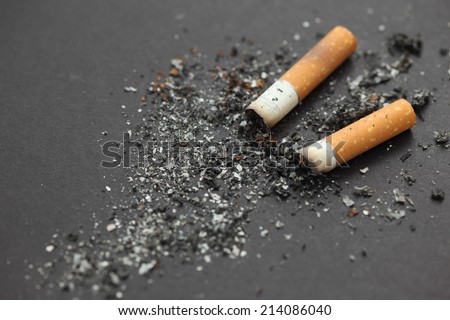 Cigarette butts with ash on black background. Closeup.