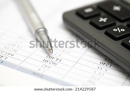 Calculator, ballpoint pen on financial statements. Closeup.