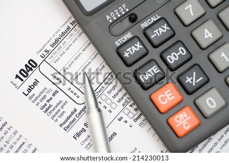 1040 Tax Form with ballpoint pen and calculator. Focus on tax form. Closeup.