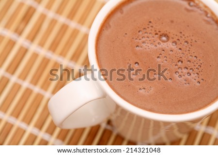 Cup of cocoa with milk on bamboo napkin. Closeup.