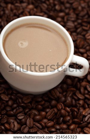 Cup of coffee with milk on coffee beans background (White coffee mug). Closeup.