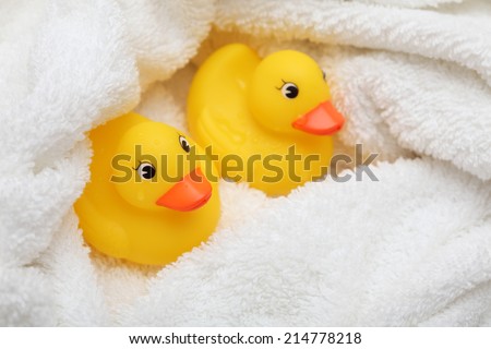 Rubber ducks after bath wrapped in a white soft towel.