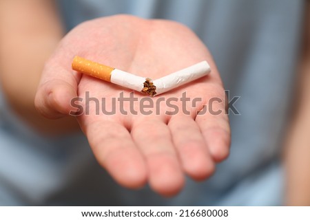 Man trying to quit smoking. A broken cigarette on the palm. Conceptual image.