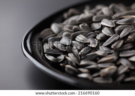 Sunflower seeds in a black plate on black background. Close-up.