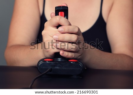 Young woman plays video game with a retro joystick. Gaming joystick from the mid-1980s. Joystick with dust particles and scratches.