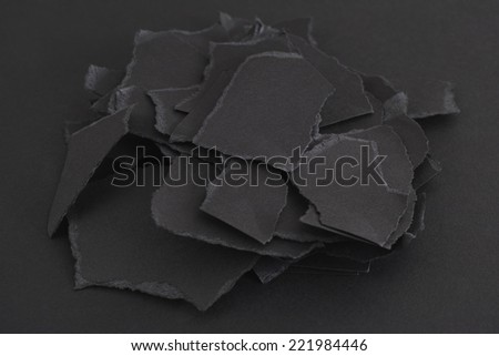 Torn pieces of black paper on a black background.
