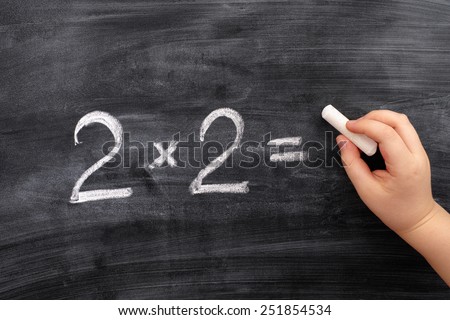 Child solving math problem on the blackboard. Multiplication.