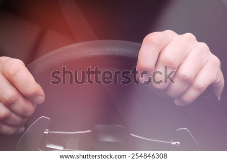 Woman hands on steering wheel of a car. Photo was taken through the windshield.