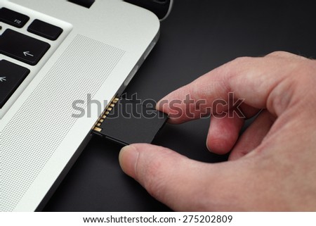 Inserting SD Card into a laptop computer. Closeup.