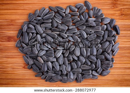 Pile of sunflower seeds on a wooden background.