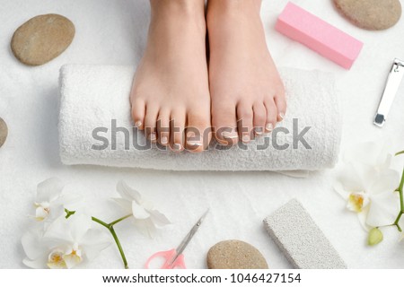 Female feet on towel roll. Nails getting a fresh and accurate look during a pedicure procedure.