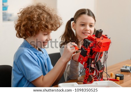 Friends assembles an electronic robot together. Boy and girl enjoy engineering classes, having fun and happy mood.