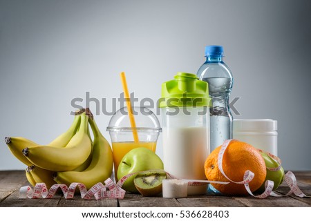 Healthy nutrition in the foreground. Tasty fruits and udeful drinks with a spoon of protein covered by a tape-measure. Nice menu for a diet.