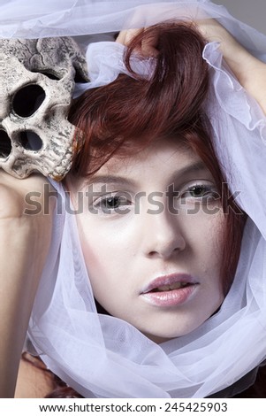 Portrait of red-haired girl with a wedding veil and skull.