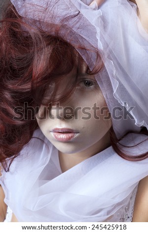 Portrait of red-haired girl with a wedding veil.