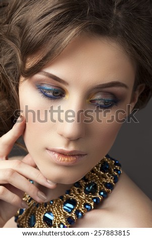 Retro hairstyle. Beautiful Brunette Woman. Fashion portrait with jewerly.On gray background.Hand near her face.