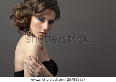 Retro hairstyle. Beautiful Brunette Woman. Fashion portrait with jewerly.On gray background.