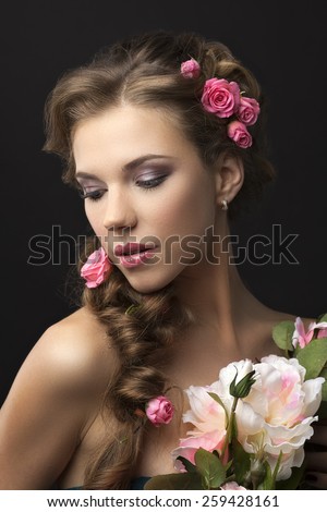 Portrait of a girl with roses in her hair on a black background.Closed eyes.