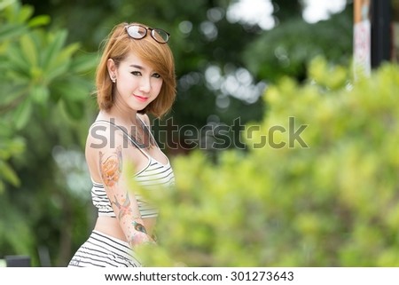Beautiful Asian Women A tattoo on the body is happy in the park in the morning.