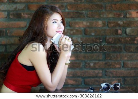 Beautiful asian woman relaxing alone at the table. The background is the old brick wall