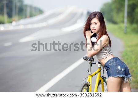 Asian women listening to music on headphones after riding an exercise bike on the road. during the summer happily.