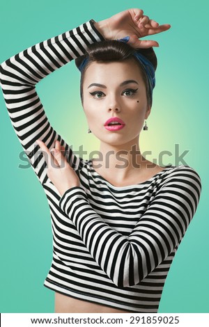 Beautiful young woman with pin-up make-up and hairstyle posing in studio with white board.\
Pin up