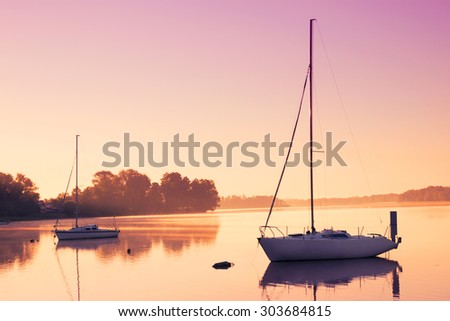 Little sailing boats reflect in  the serene water during sunrise.
