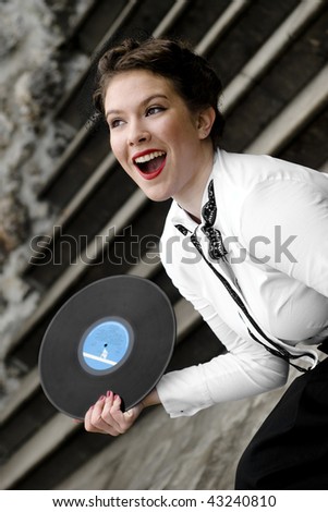 Young attractive women dressed in forties style, swing era, holding vinyl record.