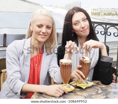cute smiling women drinking a coffee sitting outside in a cafe bistro