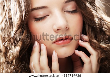 Amazing portrait of beautiful young woman with curly hair. Close-up face studio photo.