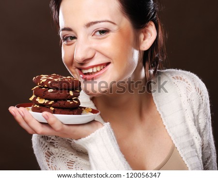 Cookie woman eating chocolate chip cookies on beige  background.