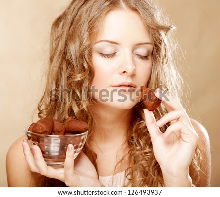 beauty portrait of a cute blond girl in act to eat a chocolate candy