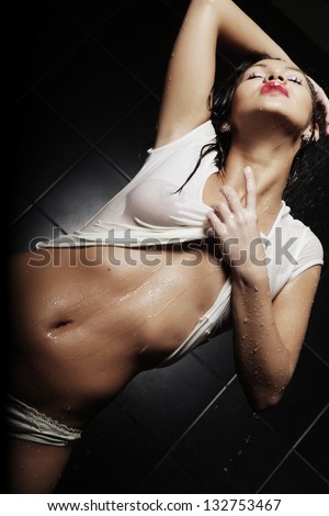 young expressive sexy  woman with T-shirt in water splashes and droplets