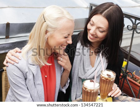 cute smiling women drinking a coffee sitting outside in a cafe bistro
