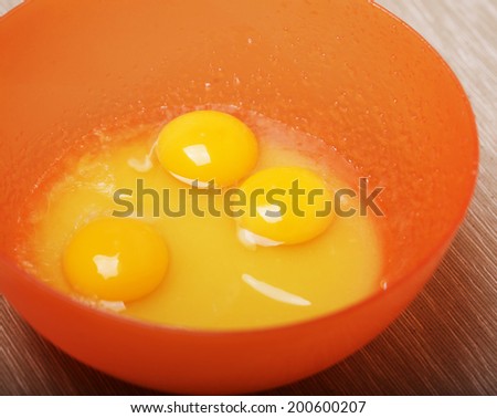 Raw egg in orange bowl
