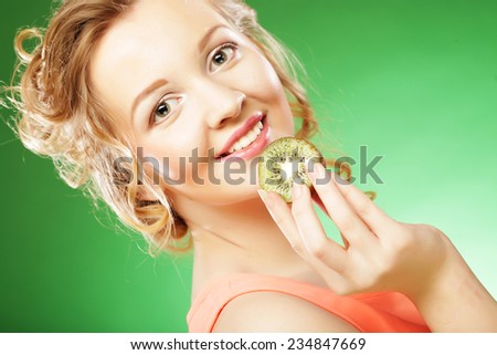 Young smiling woman holding kiwi. Over green background.