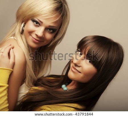 Two girl friends together smiling.Studio shot.