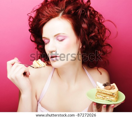 Portrait of pretty girl eating cake, close up. Pink background.