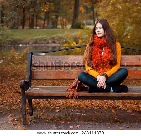 happy girl on bench in autumn park