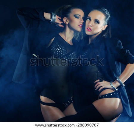 Two sexy dancing woman in black lingerie, night club.