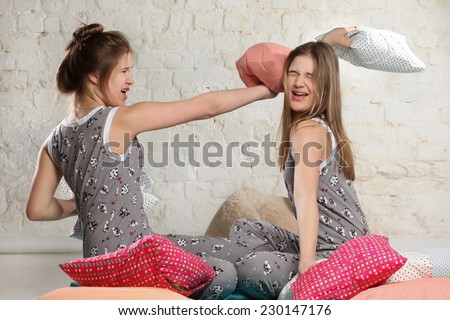 Twin sisters fighting with pillows in the bedroom