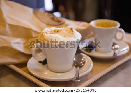 two cups of morning coffee - espresso and cappuccino - and pastries in the package on the tray